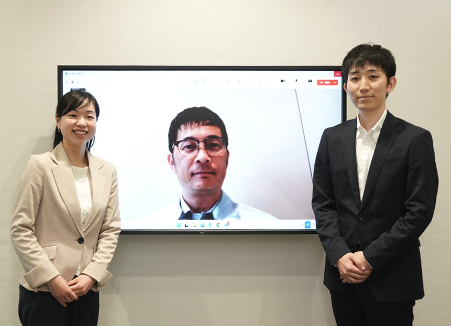 会社の外で2名が笑顔でこちらに目線を向けている。
